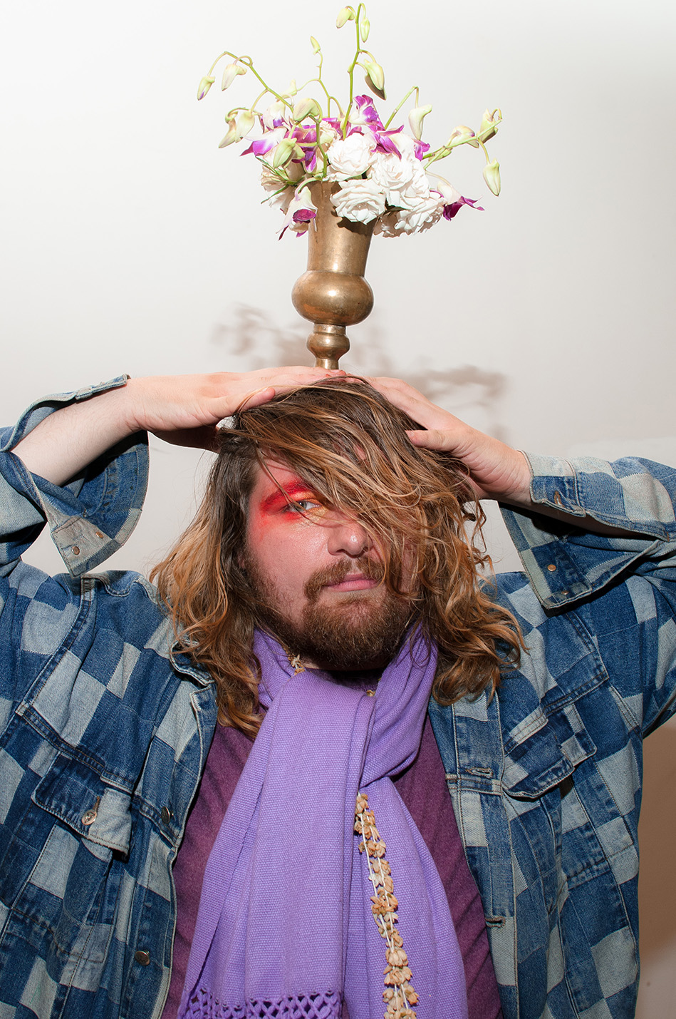 A man holding a flower vase over his head and looking at the camera